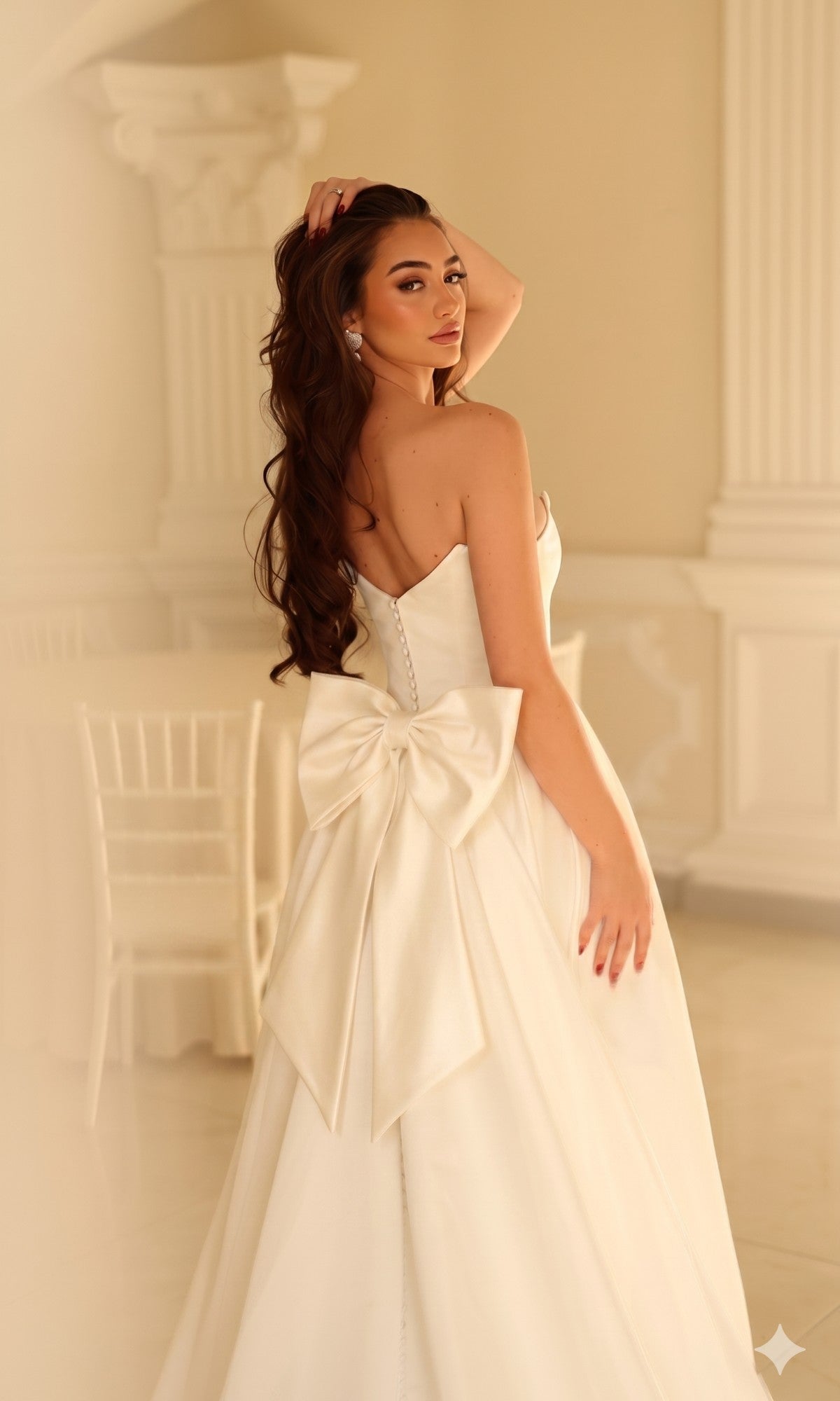 A woman wearing the Long Wedding Dress: Tina Holly TW622, a strapless satin bridal gown featuring a large bow detail on the back.